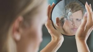 faulty self reflection 300x169 Woman holding small broken mirror